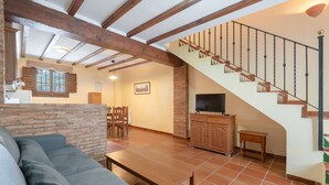 Una sala de estar con un sofá, una mesa de madera, un televisor y una escalera.