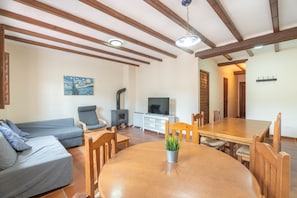 Una sala de estar con sofá, mesa de comedor, sillas, televisión y chimenea.