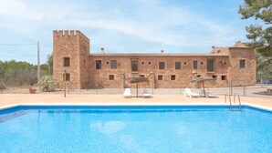 A swimming pool with lounge chairs, a stone building with a tower, and a clear sky. - Apartment 'Bruno' with Mountain View, Shared Pool and Shared Garden (Altura)