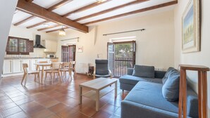 A spacious living area with a sofa, a dining table with chairs, a kitchen in the background, and a balcony with a view. - Apartment 'Bruno' with Mountain View, Shared Pool and Shared Garden (Altura)