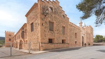 A historic stone building with a tower, a gated entrance, and a paved courtyard.