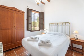 Une chambre à coucher avec un grand lit, une armoire en bois et une fenêtre avec des volets.