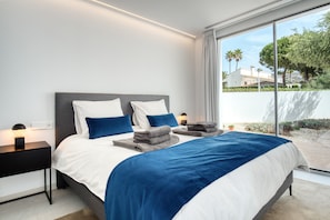 Un dormitorio moderno con una cama grande, mesitas de noche y vistas al exterior.