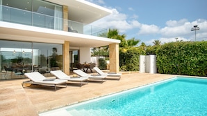 A modern house with a swimming pool, lounge chairs, and a glass-enclosed patio. - Villa 'Azul' with Mountain View, Wi-Fi and Air Conditioning (Teulada)