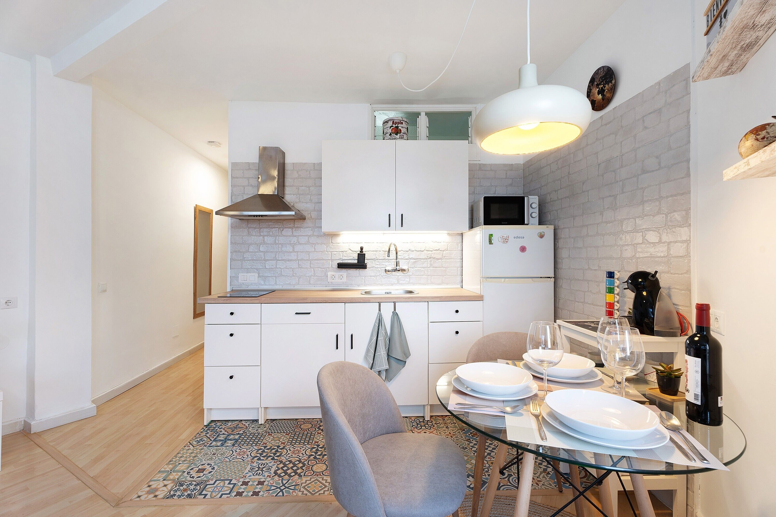 A modern kitchen with white cabinets, a microwave, and a dining area with a glass table and chairs.