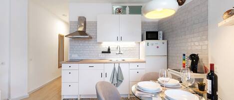 A modern kitchen with white cabinets, a microwave, and a dining area with a glass table and chairs.