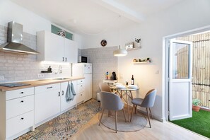 Une cuisine moderne avec des meubles blancs, un plan de travail en bois et un coin repas comprenant une table ronde et des chaises.