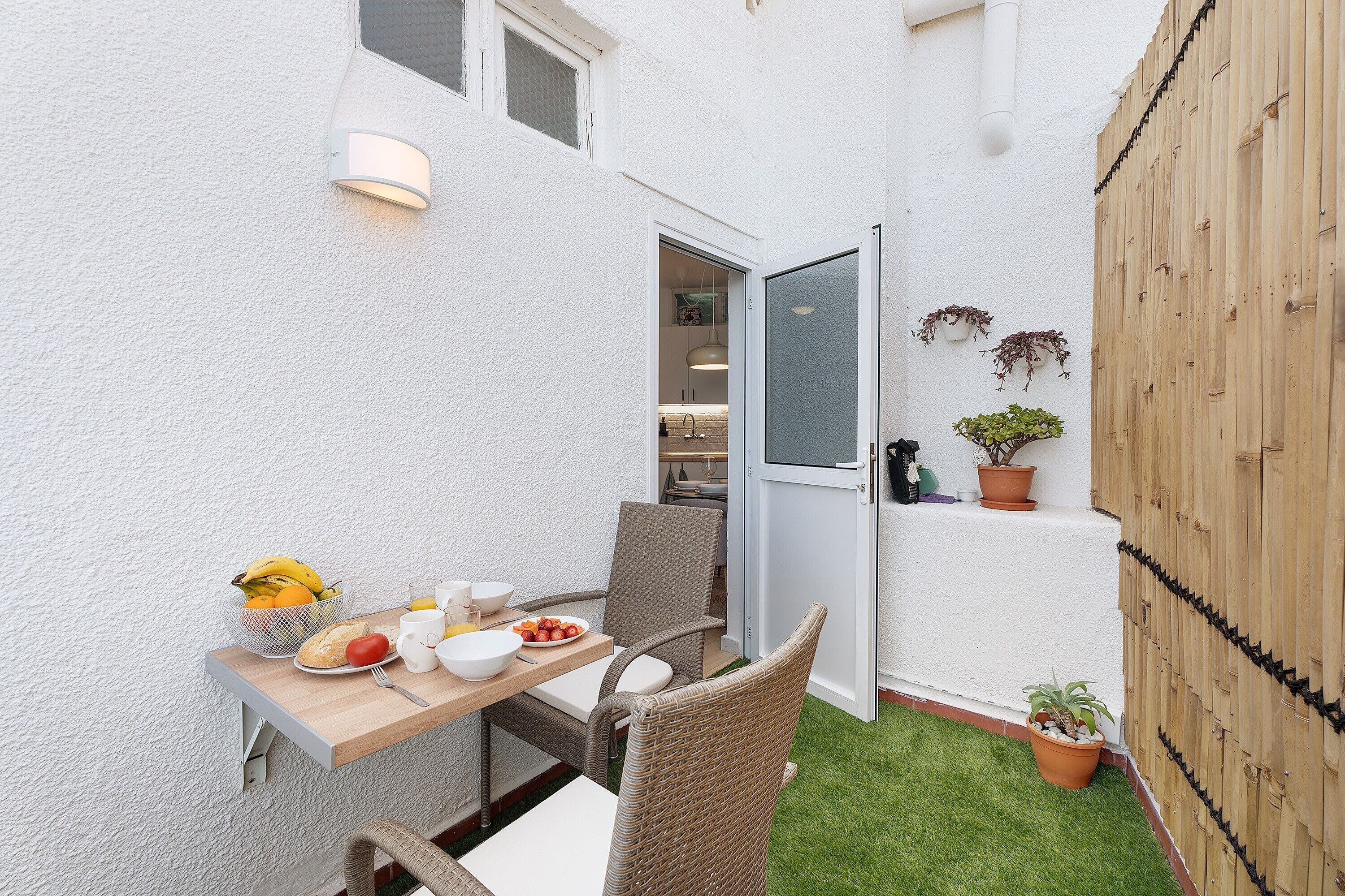 Un pequeño espacio al aire libre con mesa, sillas y plantas en macetas.