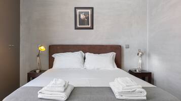 A neatly made bed with white linens, two bedside tables with lamps, and a framed picture on the wall.