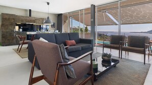 Un salon moderne avec un canapé, des fauteuils, une table basse et une vue sur la mer.