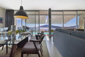 A modern dining area with a glass table, chairs, and a large pendant light. - Holiday Home 'Casa Da Quinta Dos Moinhos' with Sea View, Wi-Fi and Air Conditioning (Seixas)