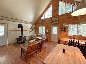 A cozy cabin interior with a wooden interior, a sofa, a dining table, and a fireplace.