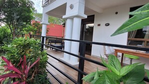 Um edifício com fachada branca, deck de madeira e guarda-corpo preto.