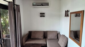 Uma sala de estar moderna com ventoinha no teto, sofá em formato de L, mesa de centro de madeira e um espelho grande.