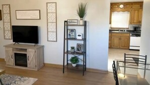 Un salon équipé d’un téléviseur à écran plat, d’un meuble en bois, d’une étagère décorative agrémentée d’une plante et d’un certificat encadré accroché au mur.