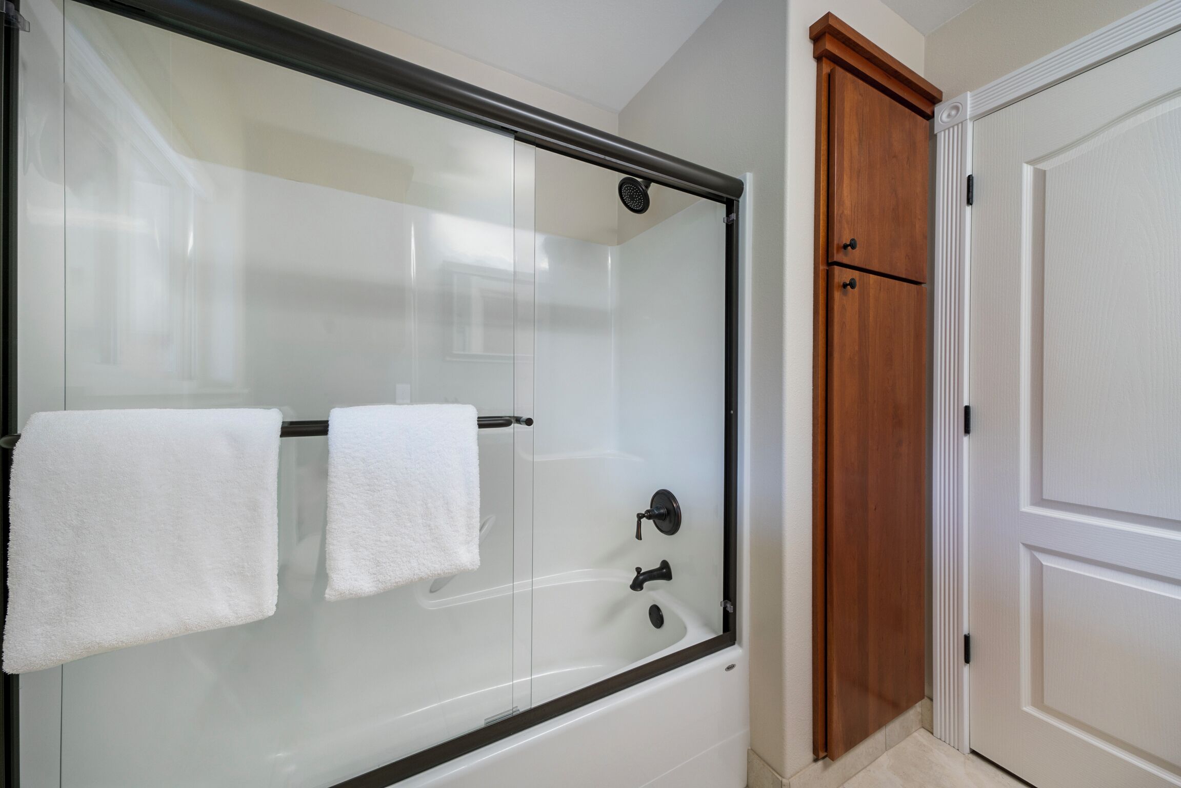 A modern bathroom with a glass-enclosed shower, a white sink, and a wooden cabinet.