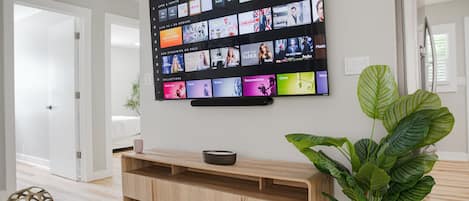 Un téléviseur à écran plat fixé au mur, affichant différentes plateformes de diffusion en continu.