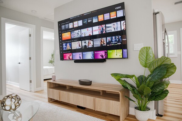 Un téléviseur à écran plat fixé au mur, affichant différentes plateformes de diffusion en continu.