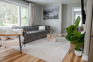 Un salon moderne avec un canapé gris, une table basse en verre et une grande plante verte.
