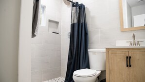 Un baño con ducha, inodoro y armario de madera.