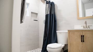 Un baño con ducha, inodoro y armario de madera.