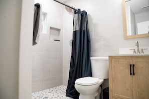 A bathroom with a shower, toilet, and wooden cabinet.