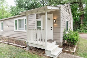 Une maison de plain-pied avec un porche à l’avant, une porte avec une fenêtre et un petit jardin.