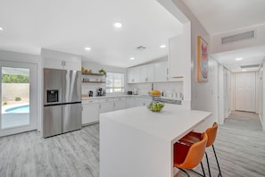 A modern kitchen with a central island, stainless steel appliances, and a view of a swimming pool.