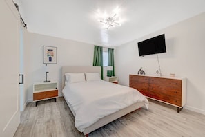 A bedroom with a bed, a TV, a dresser, and a nightstand.
