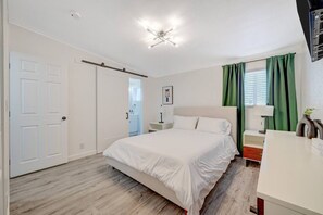 Une chambre à coucher avec un lit, une table de chevet, une lampe et une vue sur la salle de bain.