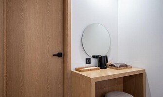 A wooden door, a round mirror, a small wooden table, and a stool.