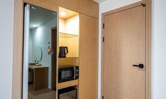 Una habitación pequeña con un armario de madera, un microondas y una tetera.