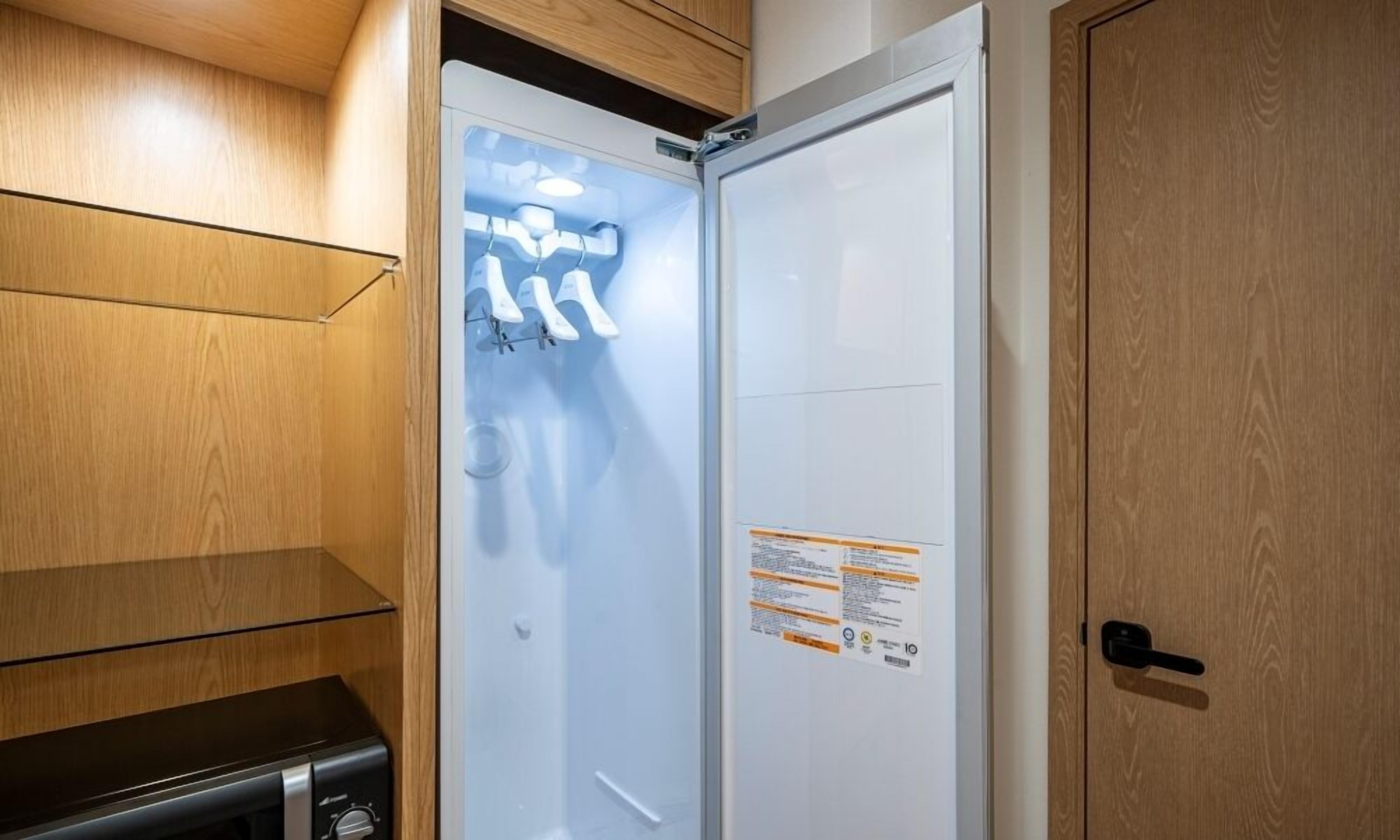 A bathroom with a white door, a wooden cabinet, and a black appliance.