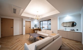 A modern living room with a sofa, a coffee table, a desk, and a chandelier.