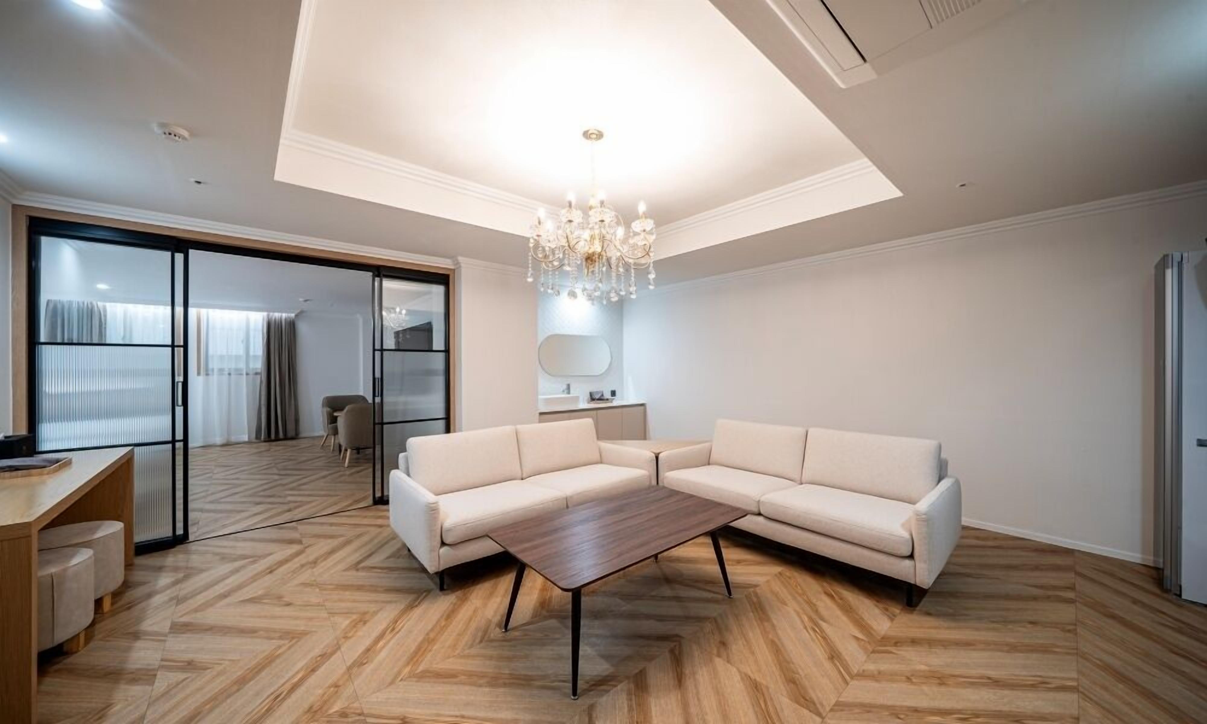 Un salon moderne avec un canapé d’angle, une table basse en bois et un lustre.