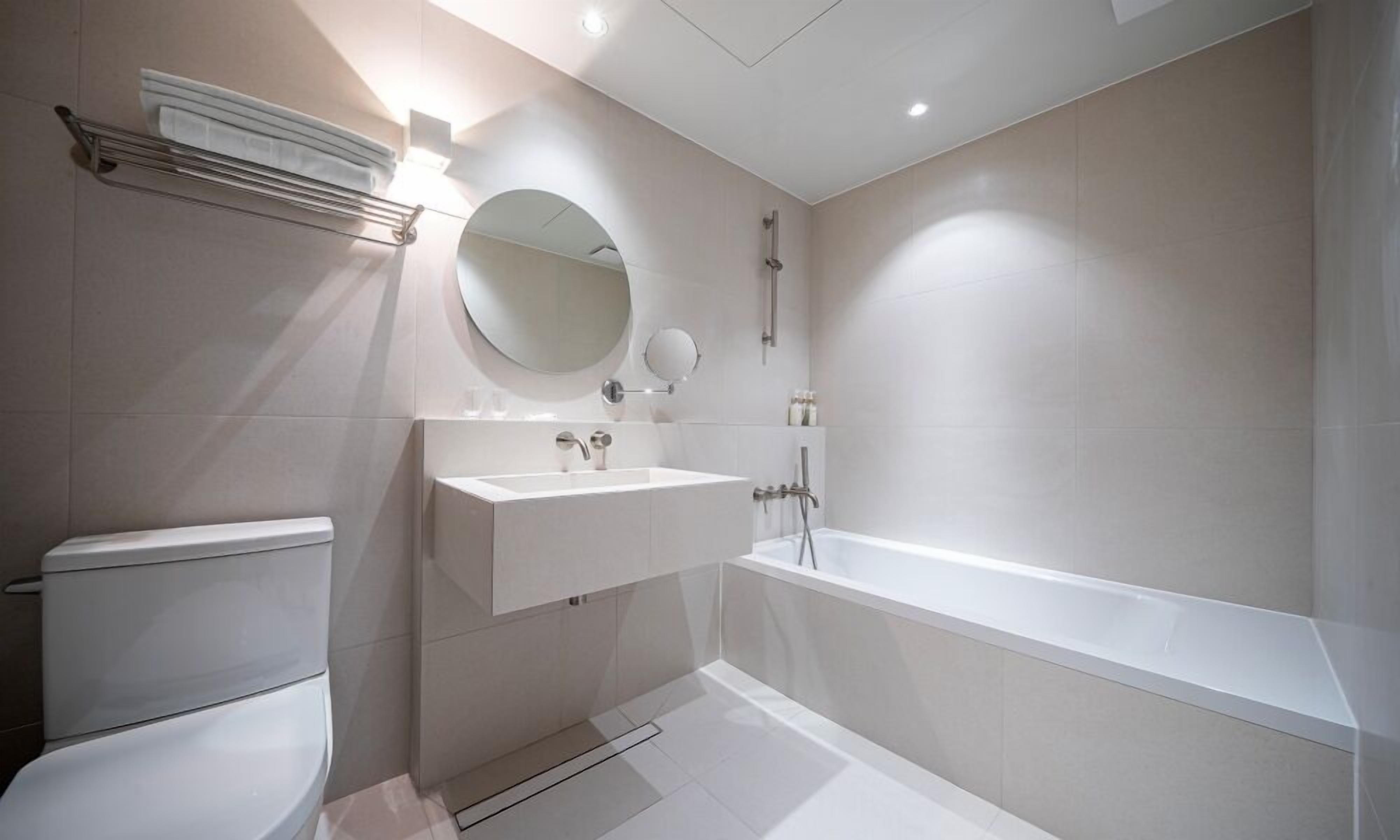 A modern bathroom with a toilet, sink, and bathtub.