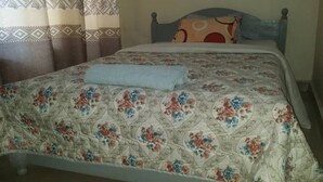 Una cama con una colcha de estampado floral y una manta azul.