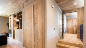 A modern interior with wooden flooring, built-in shelving, and a staircase leading to another room. - Montardo (Artíes)