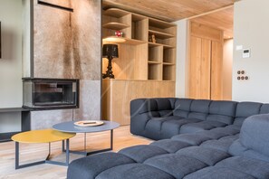 A modern living room with a sectional sofa, a small round table, and a built-in fireplace.