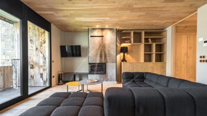 A modern living room with a sectional sofa, a fireplace, and a TV mounted on the wall. - Montardo (Artíes)