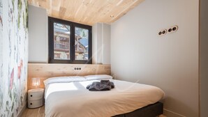 A bedroom with a wooden headboard, a large window, a bedside table, and a bed with white bedding and towels. - Montardo (Artíes)