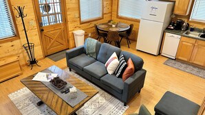 Une pièce confortable, aménagée dans le style d’un chalet, avec un canapé, une table basse et un coin repas.