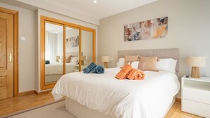Une chambre d’hôtel avec un grand lit, deux tables de chevet, un miroir et un tableau au mur.