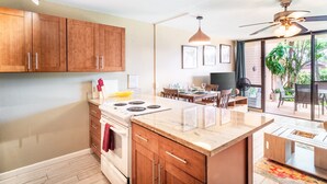 A modern kitchen with wooden cabinets, a central island, and a dining area with a table and chairs.