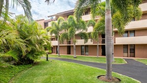 A hotel with a courtyard featuring palm trees and a well-maintained lawn.