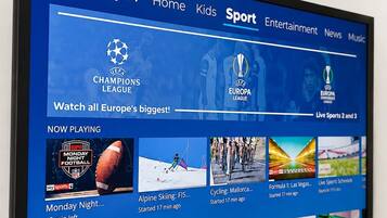 A TV screen displaying a sports channel interface with options for apps, TV, home, kids, sport, entertainment, news, and music.