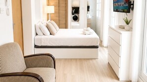 Una habitación de hotel moderna con cama, televisor, sofá y espacio para lavandería.