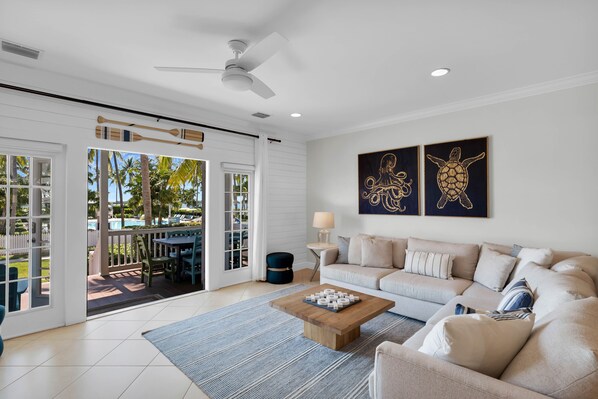A spacious living room with a large sofa, a coffee table, and a view of a pool and outdoor furniture.