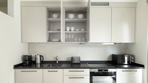 Een moderne keuken met witte kastjes, een zwart aanrecht, een ingebouwde oven en een koffiezetapparaat.