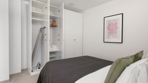 Een slaapkamer met een bed, een kledingkast en een lijst met een kunstwerk aan de muur.